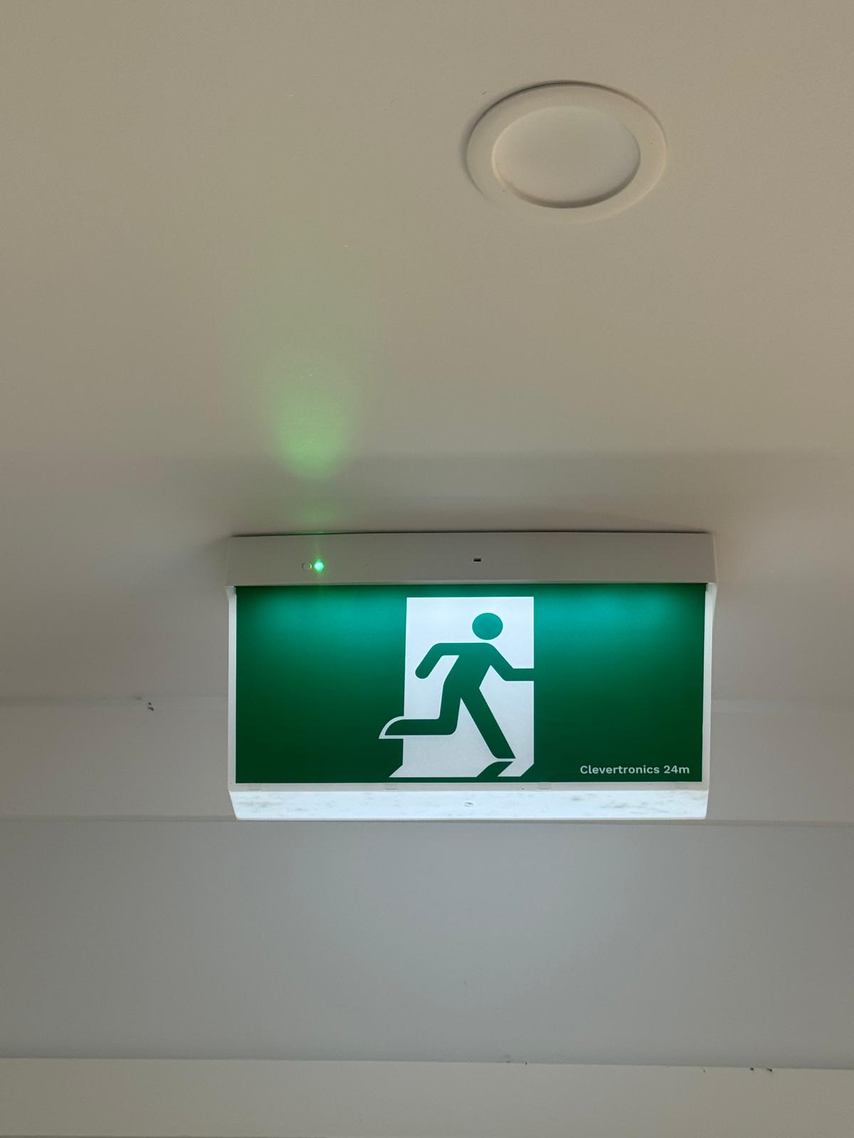 Emergency exit luminaire ceiling inspection in commercial hallway